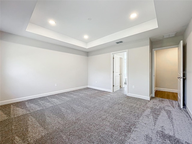 unfurnished bedroom featuring carpet floors and a tray ceiling