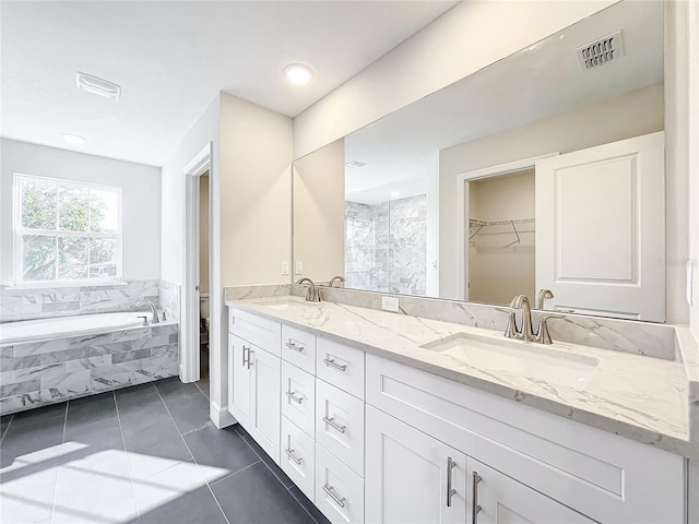 bathroom featuring tile patterned flooring, vanity, toilet, and tiled tub