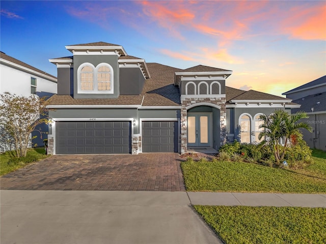 4408 Renly Ln, Clermont, FL 34711 - view of front of property featuring decorative driveway, stone siding, french doors, stucco siding, and an attached garage
