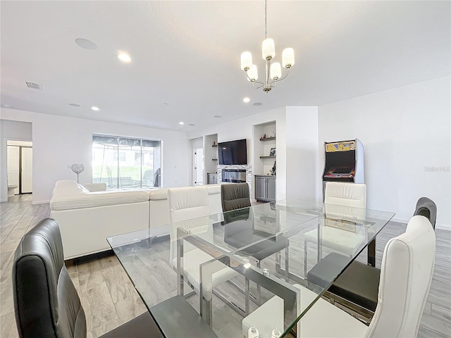 dining room featuring a notable chandelier, light wood-type flooring, and built in shelves