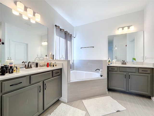 bathroom with tiled tub, tile patterned flooring, and vanity