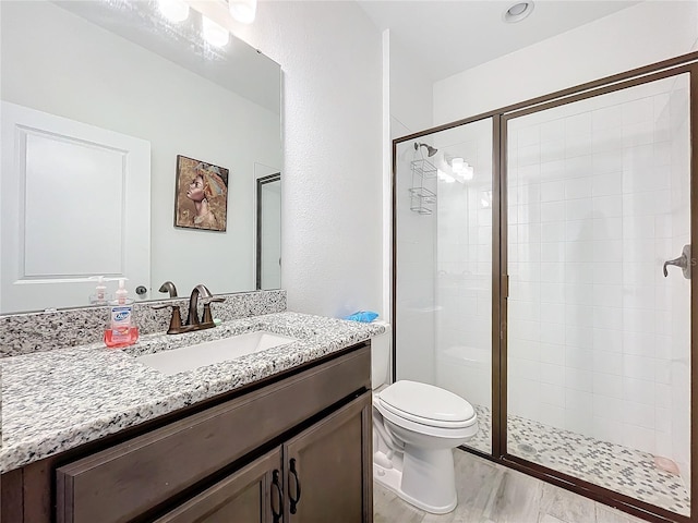 bathroom featuring vanity, toilet, wood-type flooring, and walk in shower