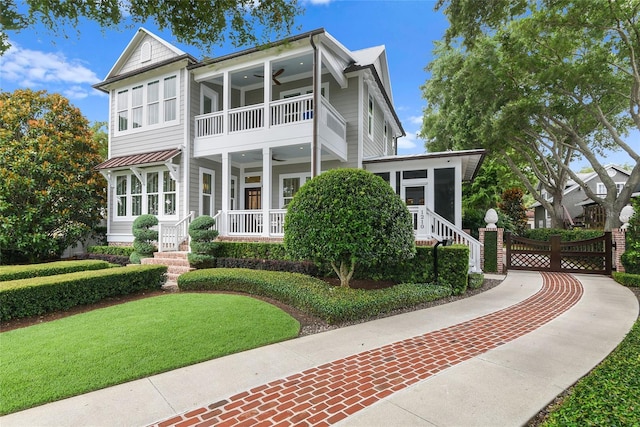 view of front of house with a front yard, a sunroom, ceiling fan, and a balcony