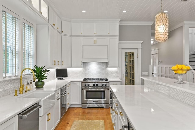 kitchen featuring white cabinets, ornamental molding, hanging light fixtures, stainless steel appliances, and a sink