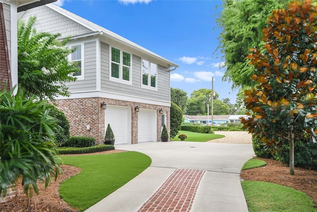 view of home's exterior with a garage, concrete driveway, brick siding, and a yard