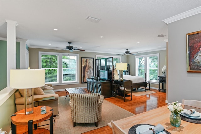 living room featuring wood-type flooring, a wealth of natural light, and crown molding