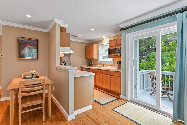 kitchen featuring a breakfast bar, brown cabinets, light wood finished floors, light countertops, and stainless steel microwave