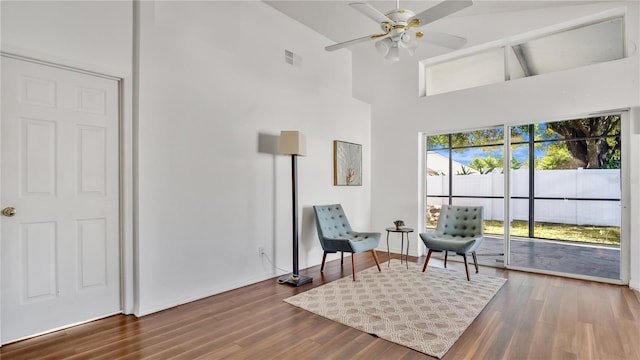 sitting room featuring ceiling fan, a high ceiling, and wood-type flooring