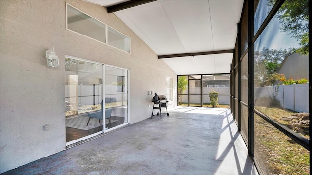 unfurnished sunroom featuring vaulted ceiling with beams