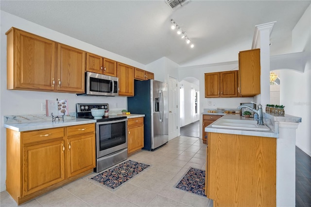 kitchen with light tile patterned floors, kitchen peninsula, stainless steel appliances, lofted ceiling, and sink