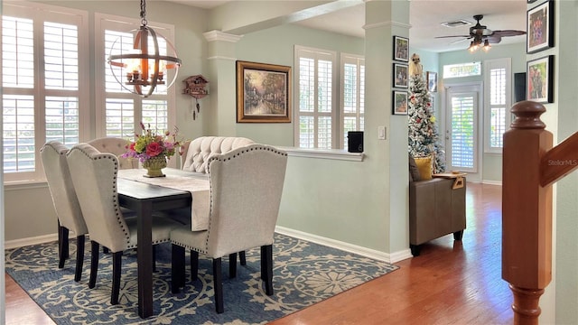 dining area with ceiling fan with notable chandelier, dark hardwood / wood-style floors, and plenty of natural light