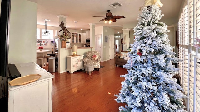 interior space with ceiling fan, dark wood-type flooring, and decorative columns