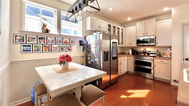 kitchen featuring dark wood-type flooring, white cabinetry, hanging light fixtures, and stainless steel appliances