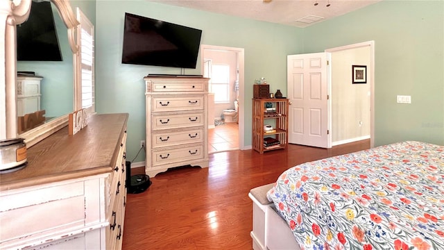 bedroom featuring a textured ceiling, dark hardwood / wood-style flooring, and ensuite bath