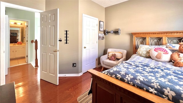 bedroom with ensuite bathroom and dark hardwood / wood-style flooring