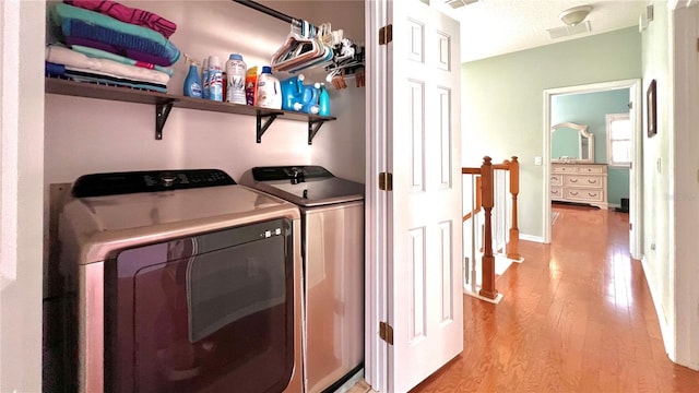 laundry area with washer and clothes dryer and light hardwood / wood-style floors