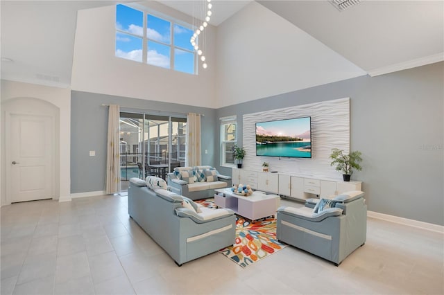 living room featuring an inviting chandelier, a towering ceiling, and ornamental molding