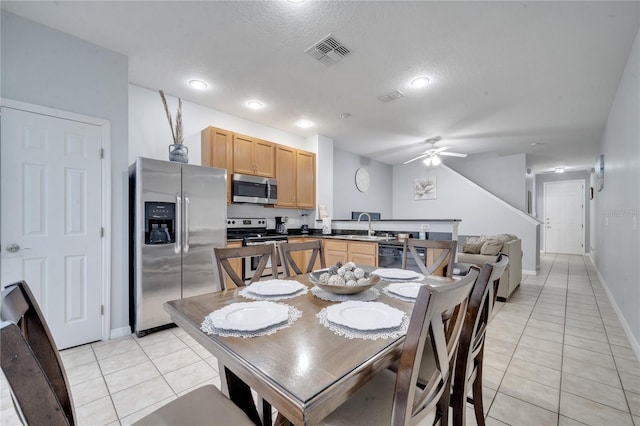 dining room featuring ceiling fan, sink, light tile patterned floors, and a textured ceiling