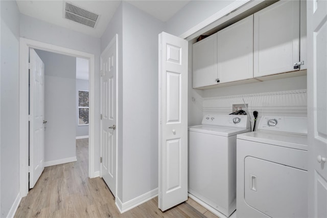 clothes washing area with light hardwood / wood-style flooring, cabinets, and independent washer and dryer