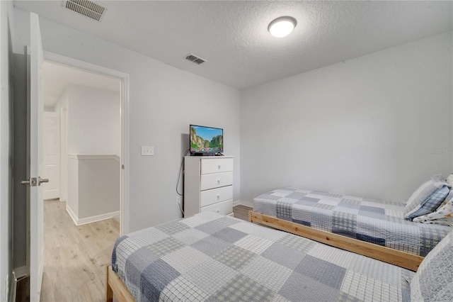 bedroom featuring a textured ceiling and light hardwood / wood-style flooring