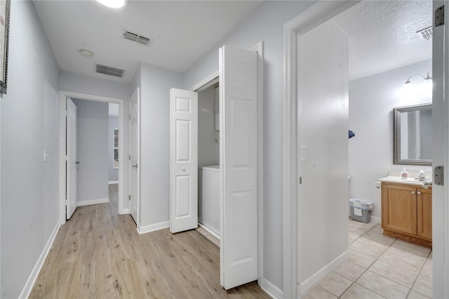 corridor with a textured ceiling and light wood-type flooring