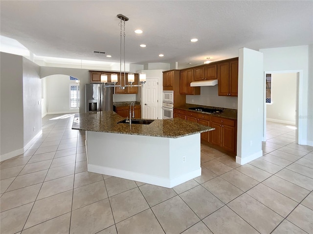 kitchen featuring pendant lighting, a kitchen island with sink, dark stone counters, sink, and stainless steel appliances