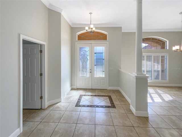 tiled entrance foyer featuring a notable chandelier, plenty of natural light, crown molding, and decorative columns