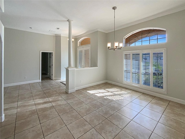 empty room with a chandelier, light tile patterned floors, crown molding, and decorative columns