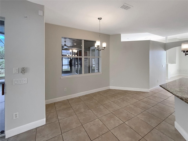 unfurnished dining area featuring ceiling fan with notable chandelier and light tile patterned floors