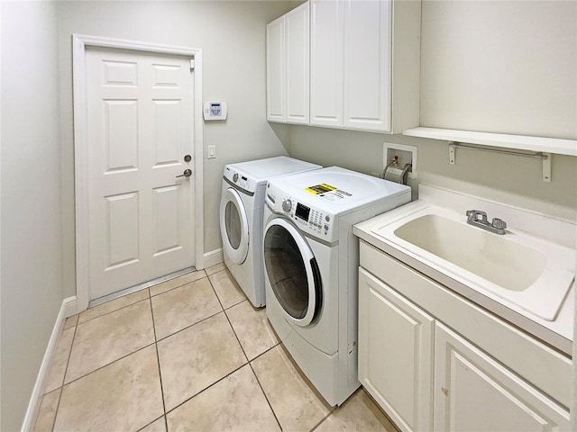 laundry area with washer and clothes dryer, sink, light tile patterned floors, and cabinets