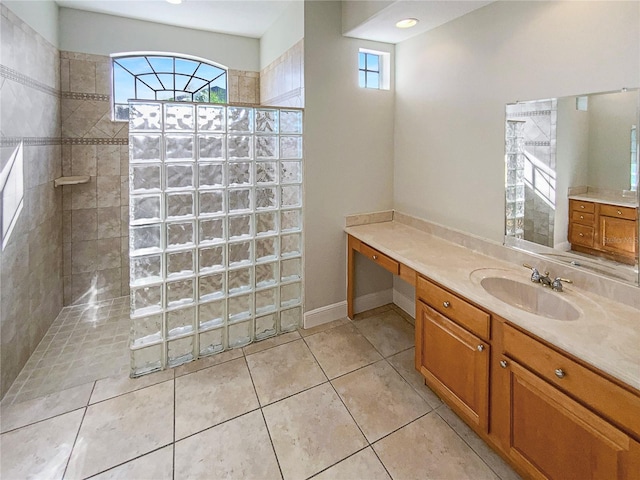 bathroom with tile patterned flooring, a tile shower, and vanity