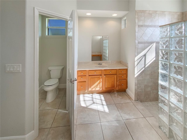 bathroom with tile patterned flooring, a tile shower, vanity, and toilet