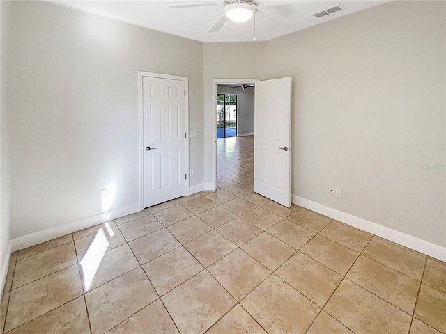 empty room with ceiling fan and light tile patterned floors