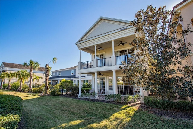 rear view of house with a lawn, ceiling fan, and a balcony