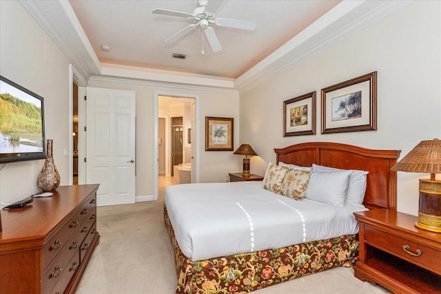 carpeted bedroom with ceiling fan, ornamental molding, a tray ceiling, and ensuite bath