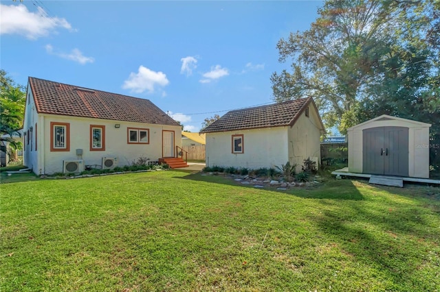 rear view of property featuring a yard, a storage shed, and ac unit