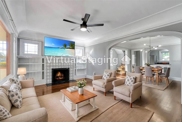 living room with ceiling fan, ornamental molding, built in features, and hardwood / wood-style flooring