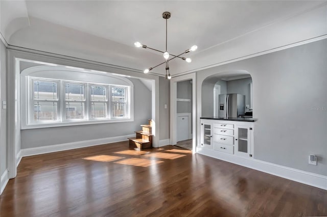 unfurnished living room with dark wood-type flooring and an inviting chandelier