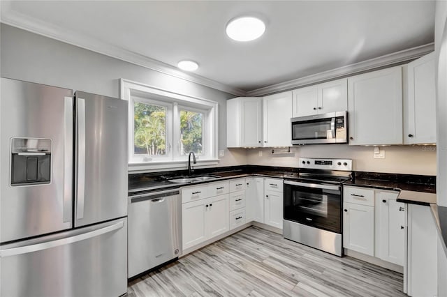 kitchen featuring white cabinets, appliances with stainless steel finishes, light hardwood / wood-style floors, sink, and crown molding