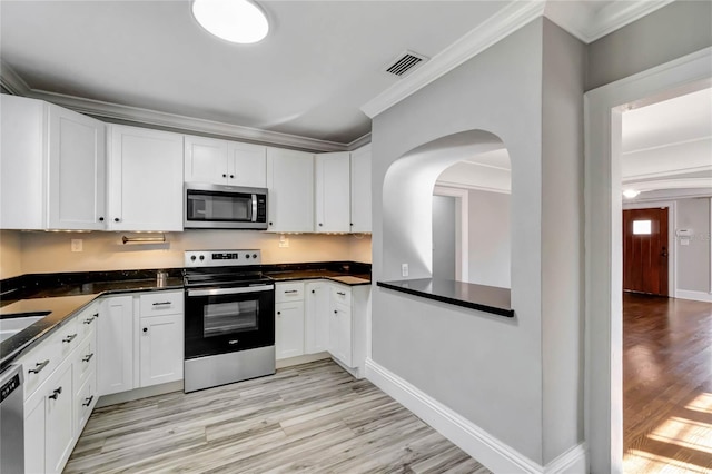 kitchen with white cabinetry, appliances with stainless steel finishes, ornamental molding, and light wood-type flooring