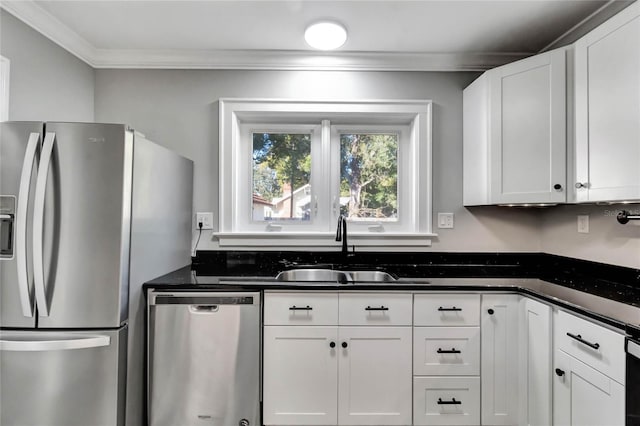 kitchen with white cabinetry, stainless steel appliances, dark stone counters, crown molding, and sink