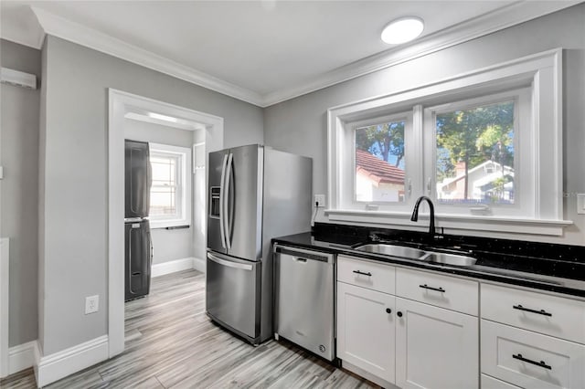 kitchen featuring appliances with stainless steel finishes, white cabinetry, light hardwood / wood-style floors, sink, and crown molding