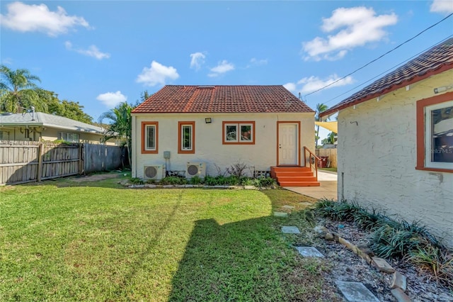 rear view of property featuring ac unit and a lawn