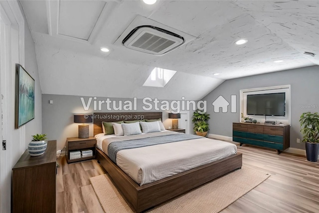 bedroom featuring lofted ceiling with skylight and light wood-type flooring