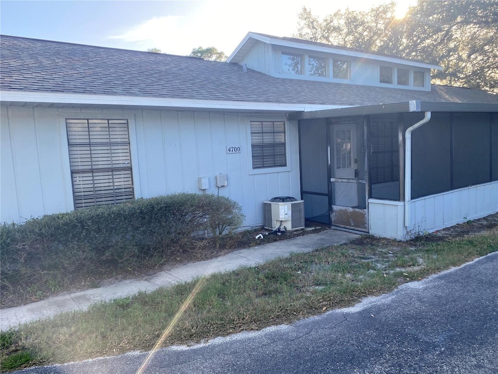 view of front of house with central AC unit and a sunroom