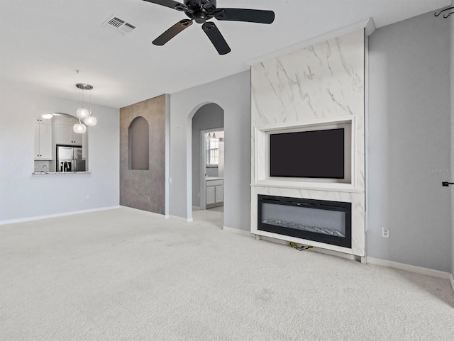 unfurnished living room featuring light colored carpet, ceiling fan, and a premium fireplace