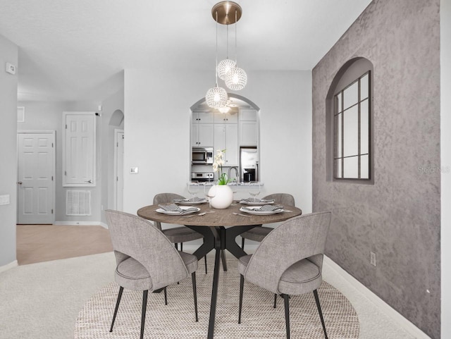 dining area with sink, light carpet, and a chandelier