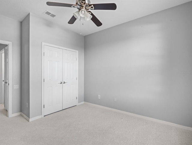 unfurnished bedroom featuring ceiling fan, light colored carpet, and a closet