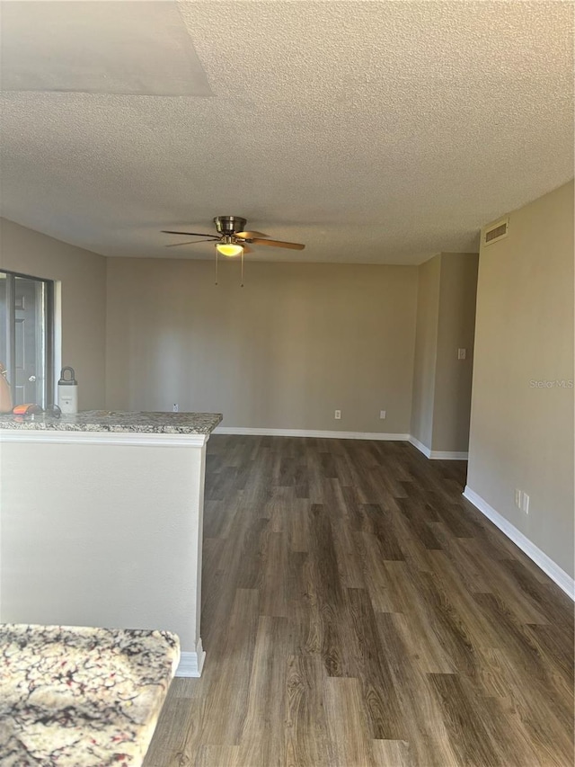 interior space featuring ceiling fan, a textured ceiling, and dark hardwood / wood-style flooring