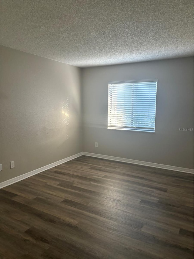 unfurnished room with a textured ceiling and dark hardwood / wood-style floors